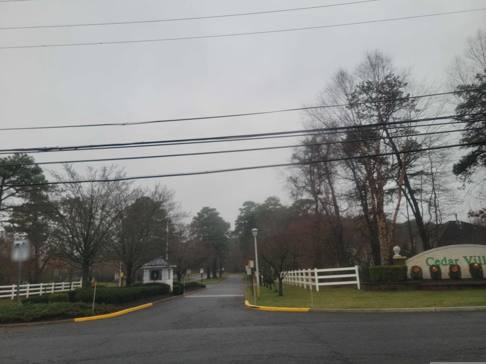 Entrance road between white fences leading to a small entrance building