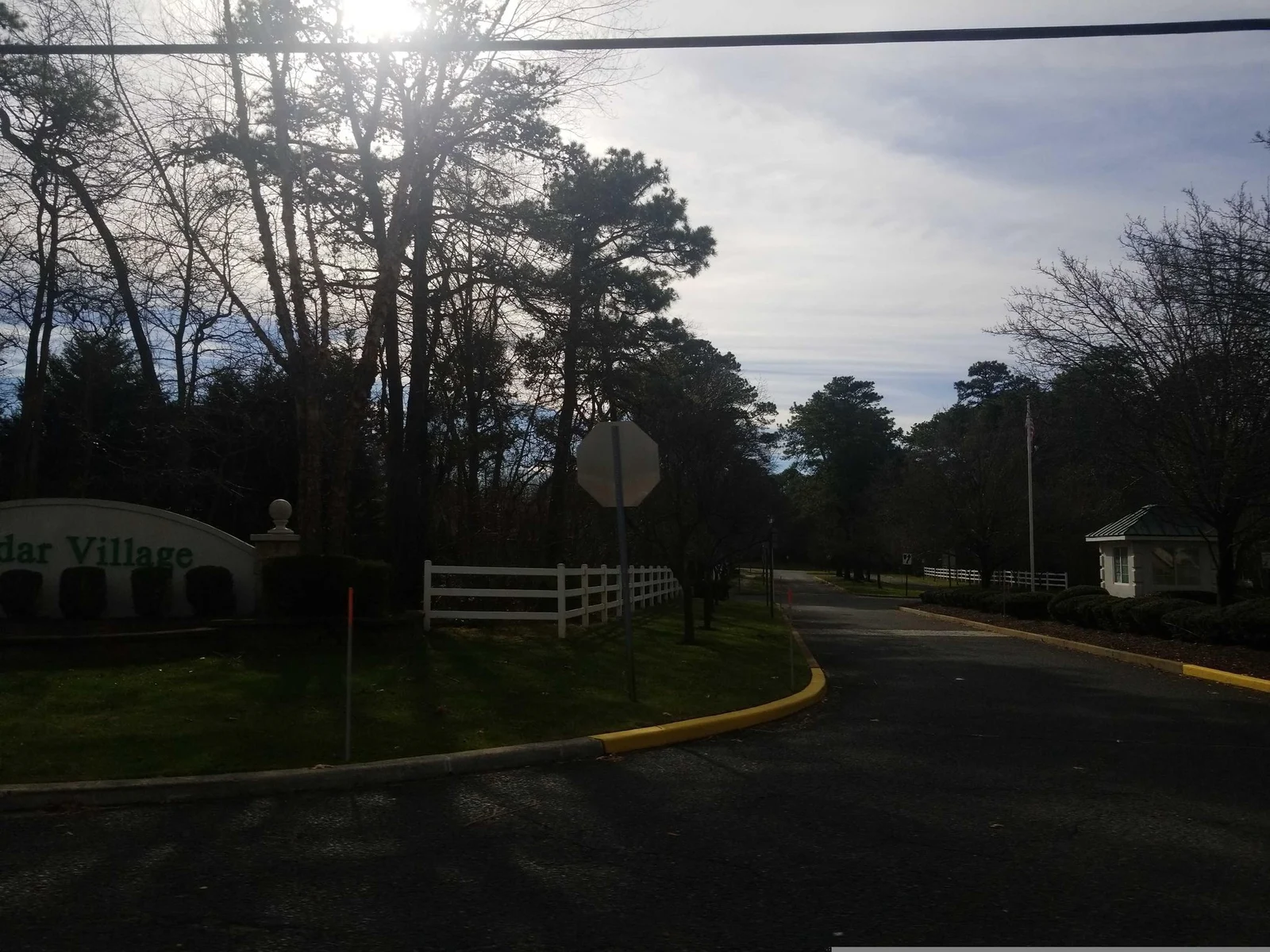 Entrance road with yellow curbs and a white fence
