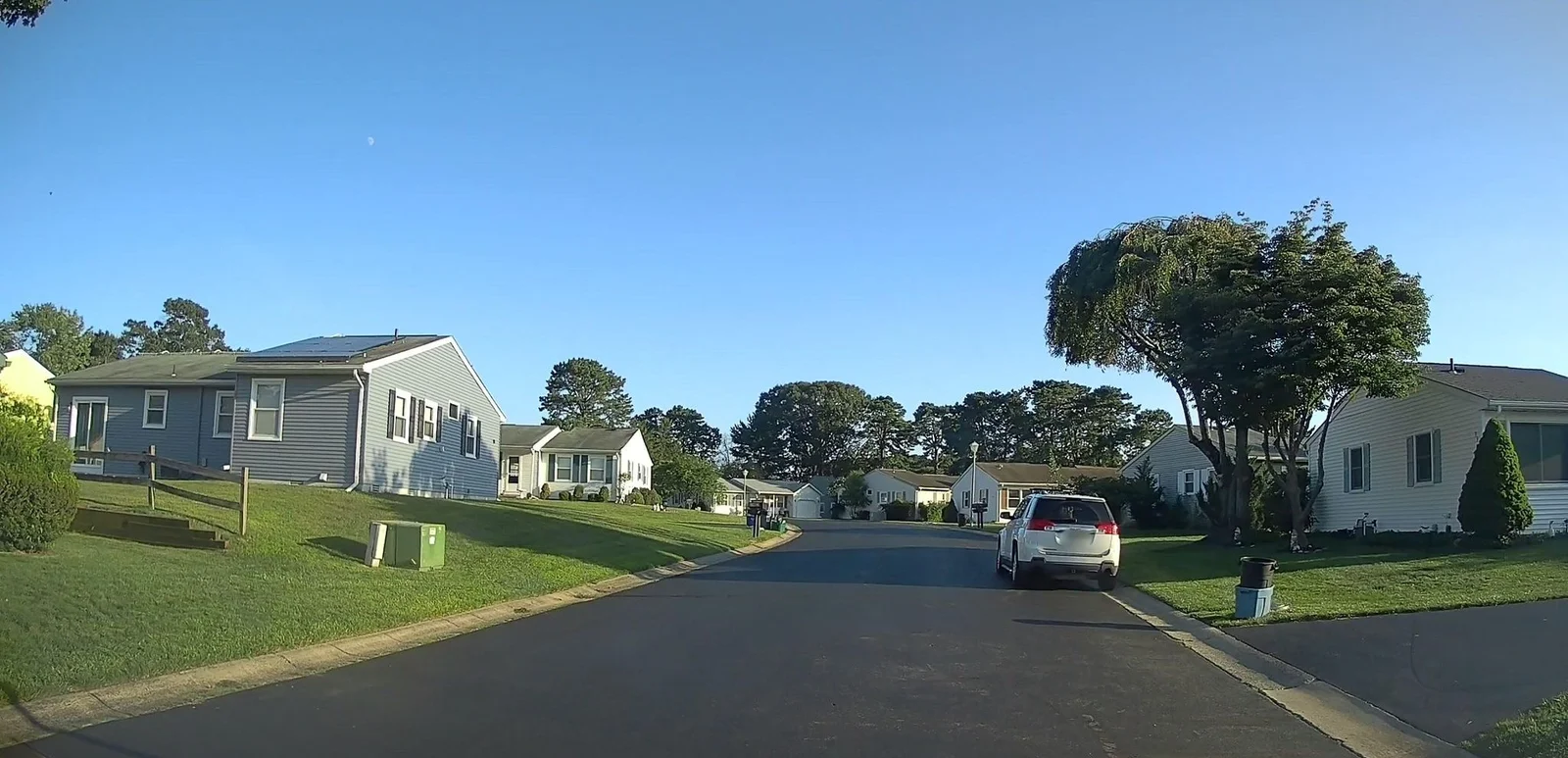 Street of single-story homes with lawns under a blue sky