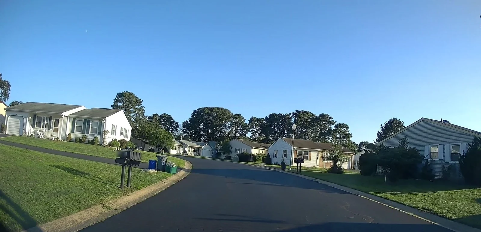 Wide street lined with single-story homes and trees