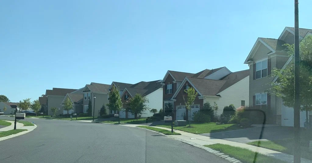 Wide curved street with brick-front and sided homes and manicured lawns