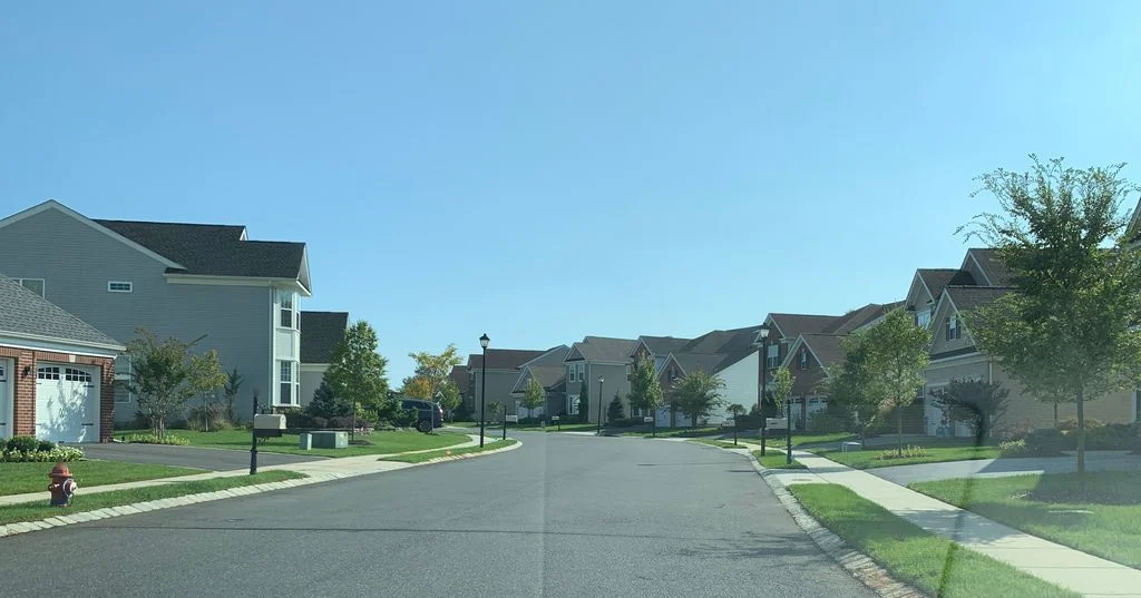 Two-story homes with garages beside a sidewalk and lamp posts