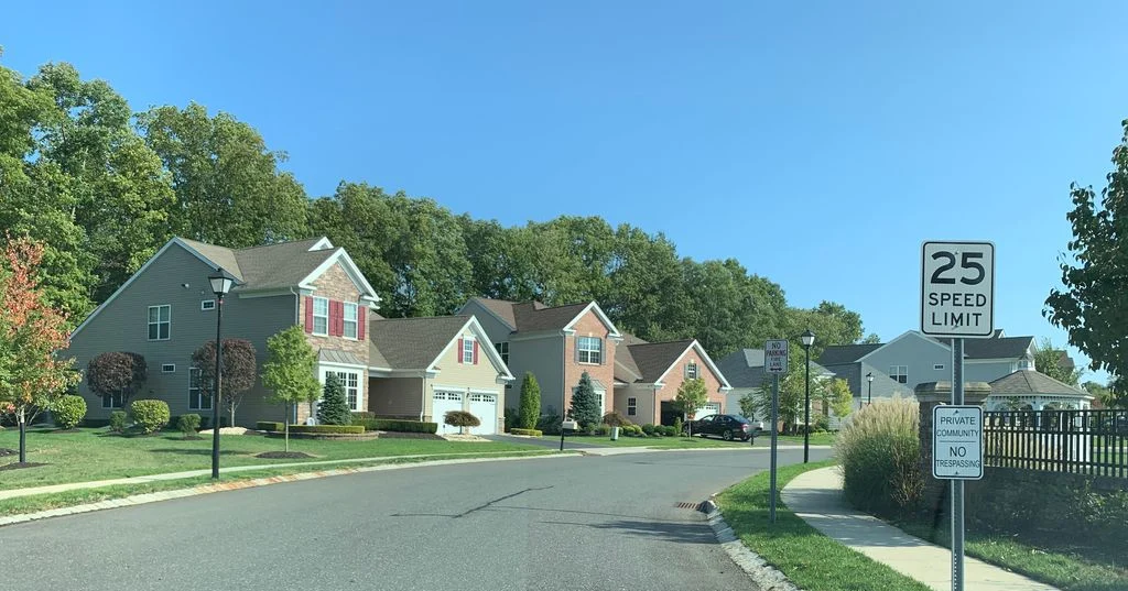 Residential street with a 25 mph speed limit sign and homes behind a fence line