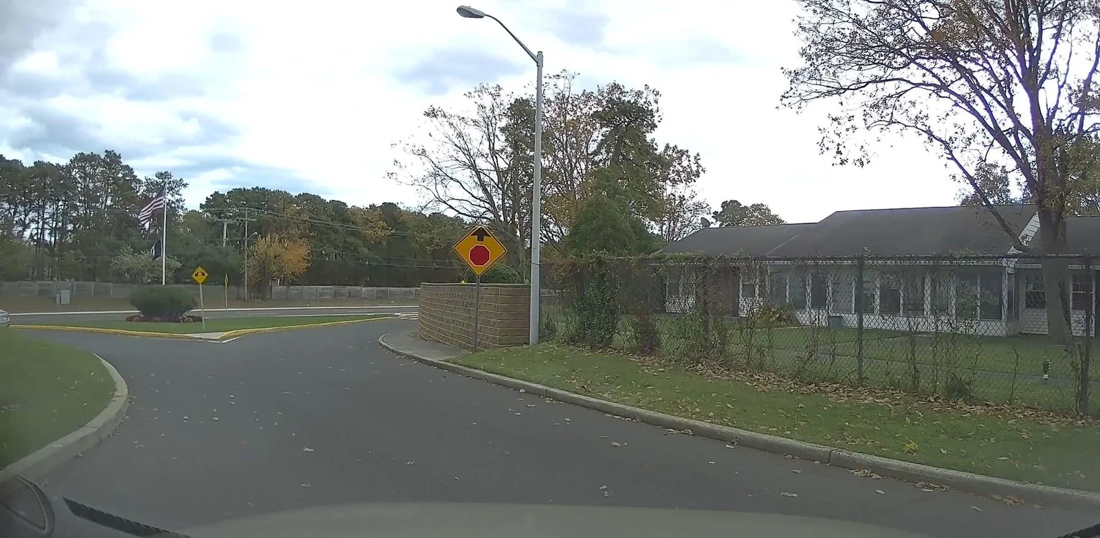 Row of single-story attached homes behind a lawn and hedges