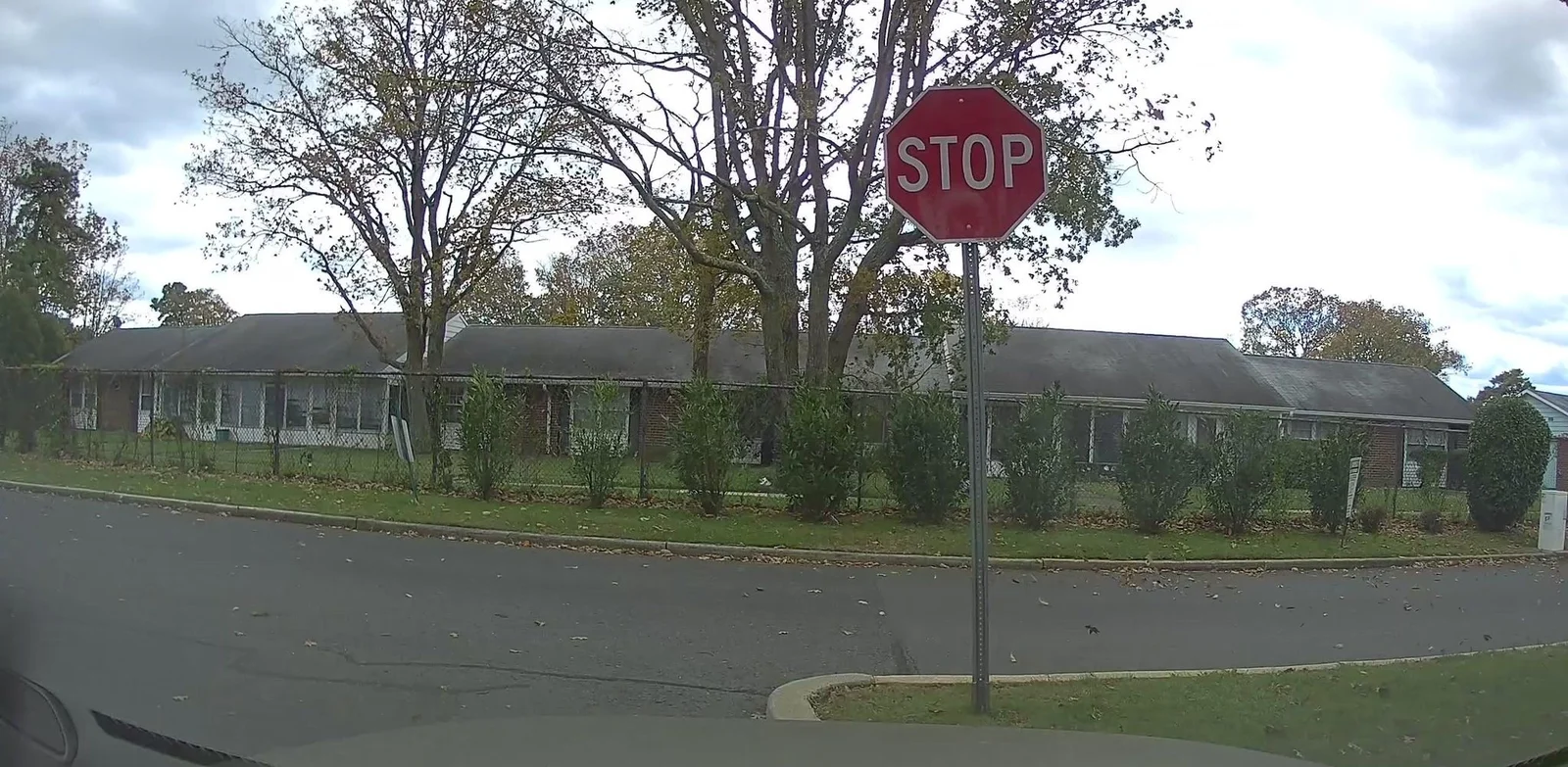 Long single-story attached homes behind a lawn and shrubs