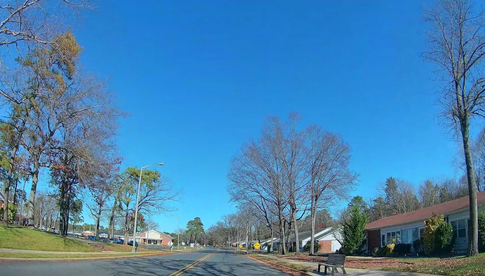 Single-story attached homes with lawns and bare autumn trees along a village street