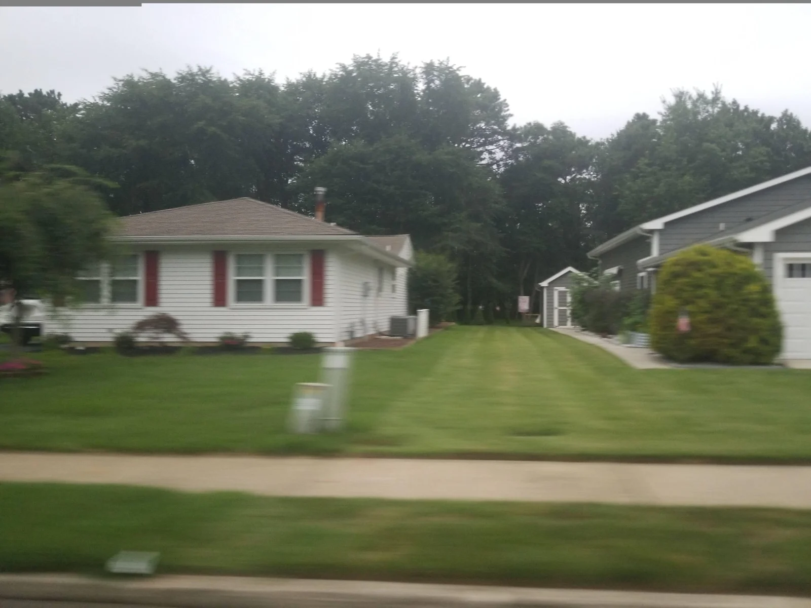 White single-story home with red shutters and a wide front lawn