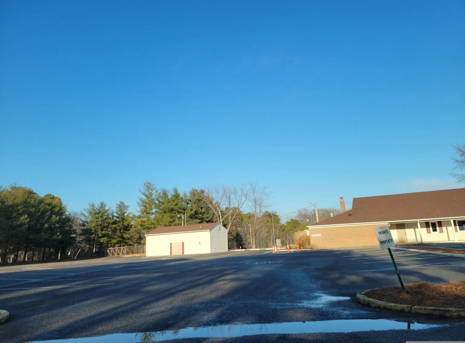 Clubhouse parking area with a small outbuilding and pine trees
