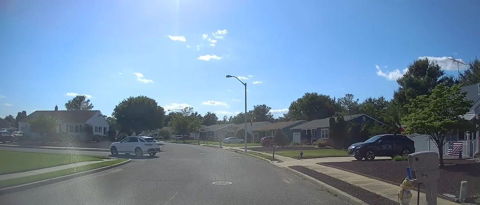 Residential street with homes on both sides under a blue sky
