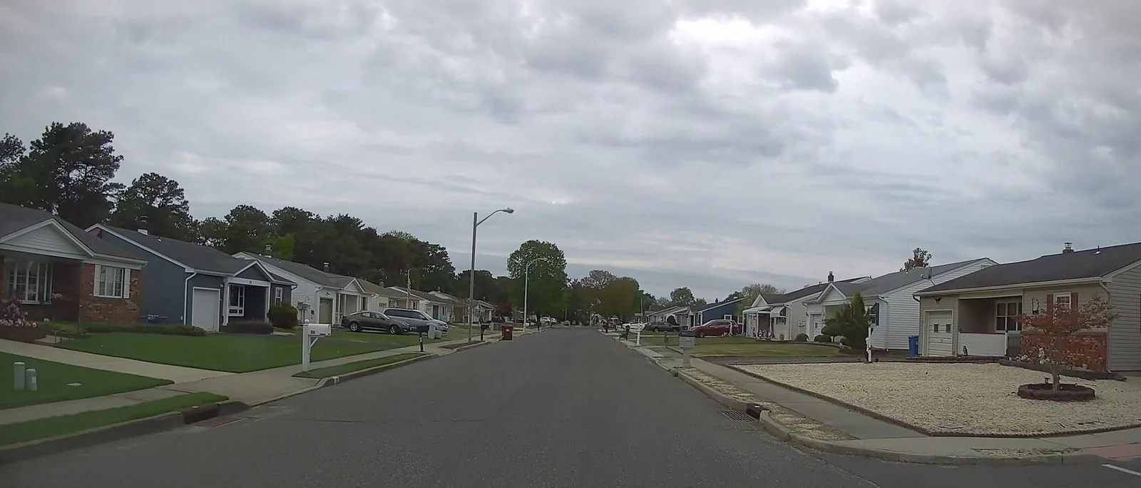 Single-story homes along a residential street under a cloudy sky