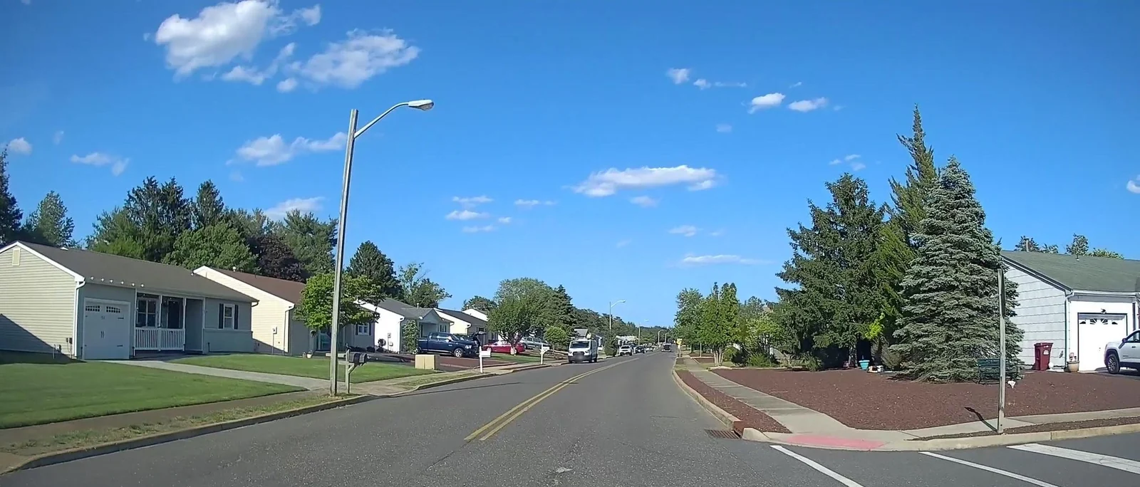 Residential street with single-story homes and evergreen trees