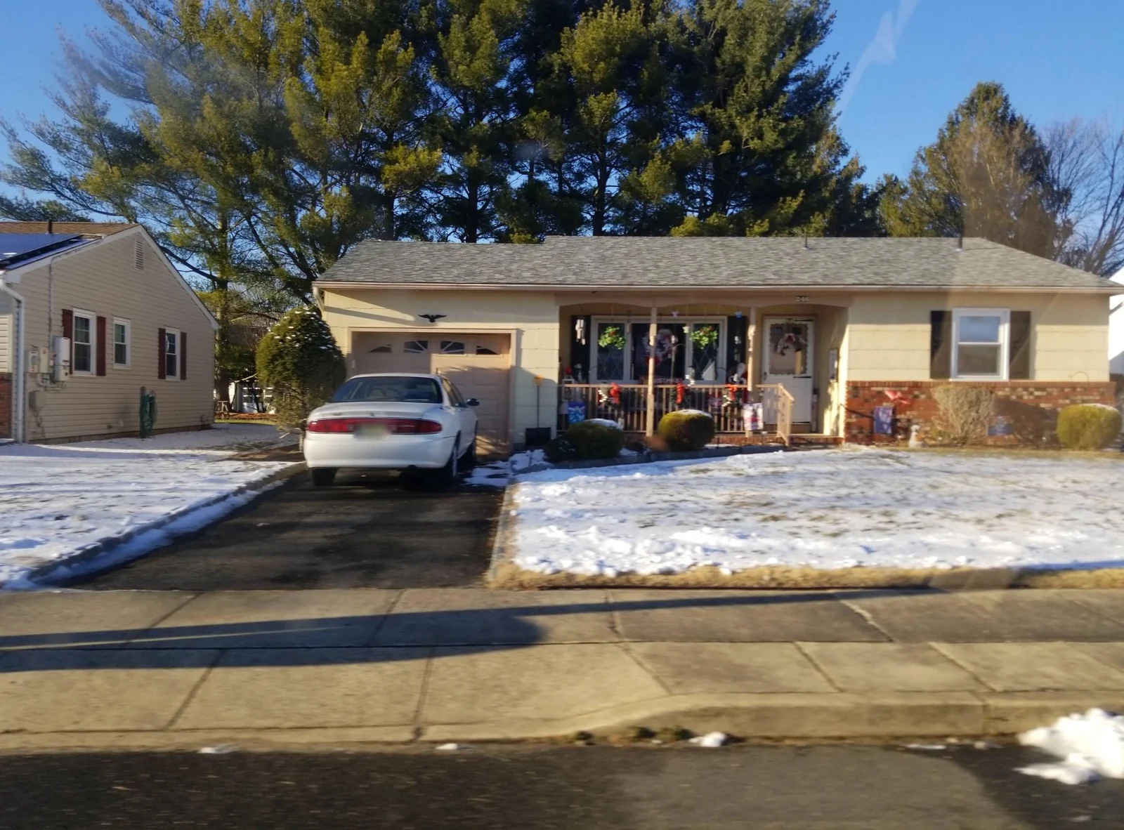 Single-story home with a driveway after a light snow