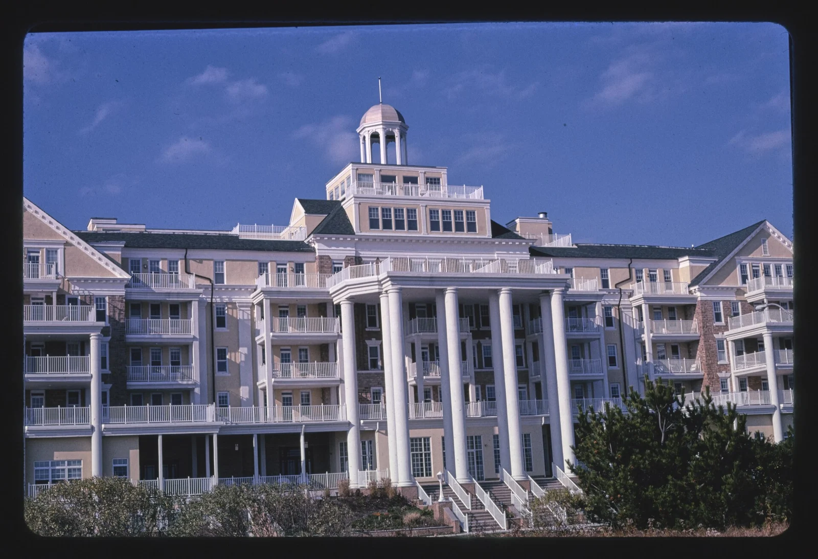 Front of the Essex and Sussex with tall white columns, balconies and a cupola under a blue sky