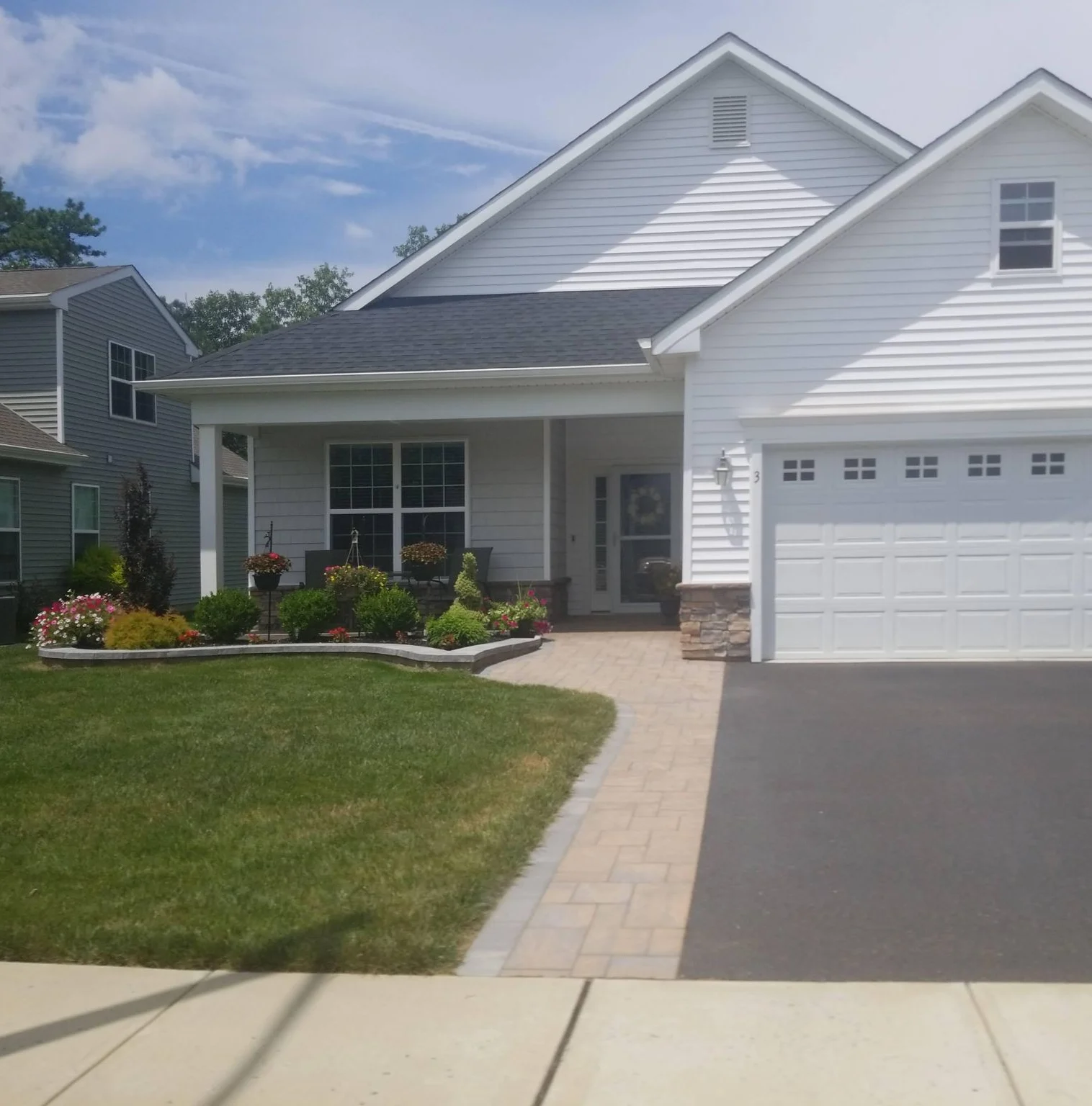 Two-tone home with a porch, paver walk and white garage door