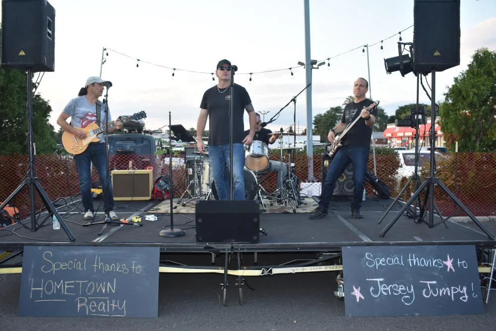 A rock band playing on an outdoor stage under string lights at Aberdeen Day