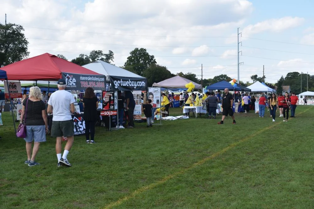 Visitors strolling past rows of vendor tents on a grass field at Aberdeen Day