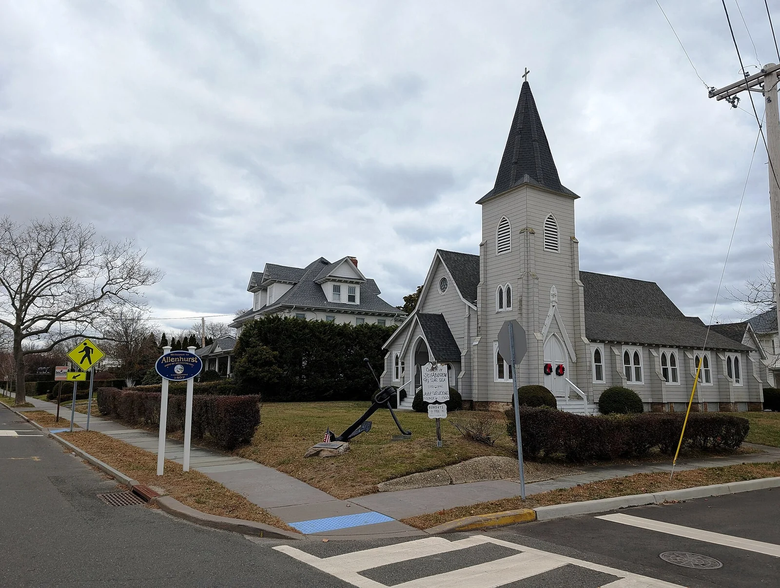 White wooden Church of St. Andrew By The Sea with a tall steeple, on a corner in Allenhurst