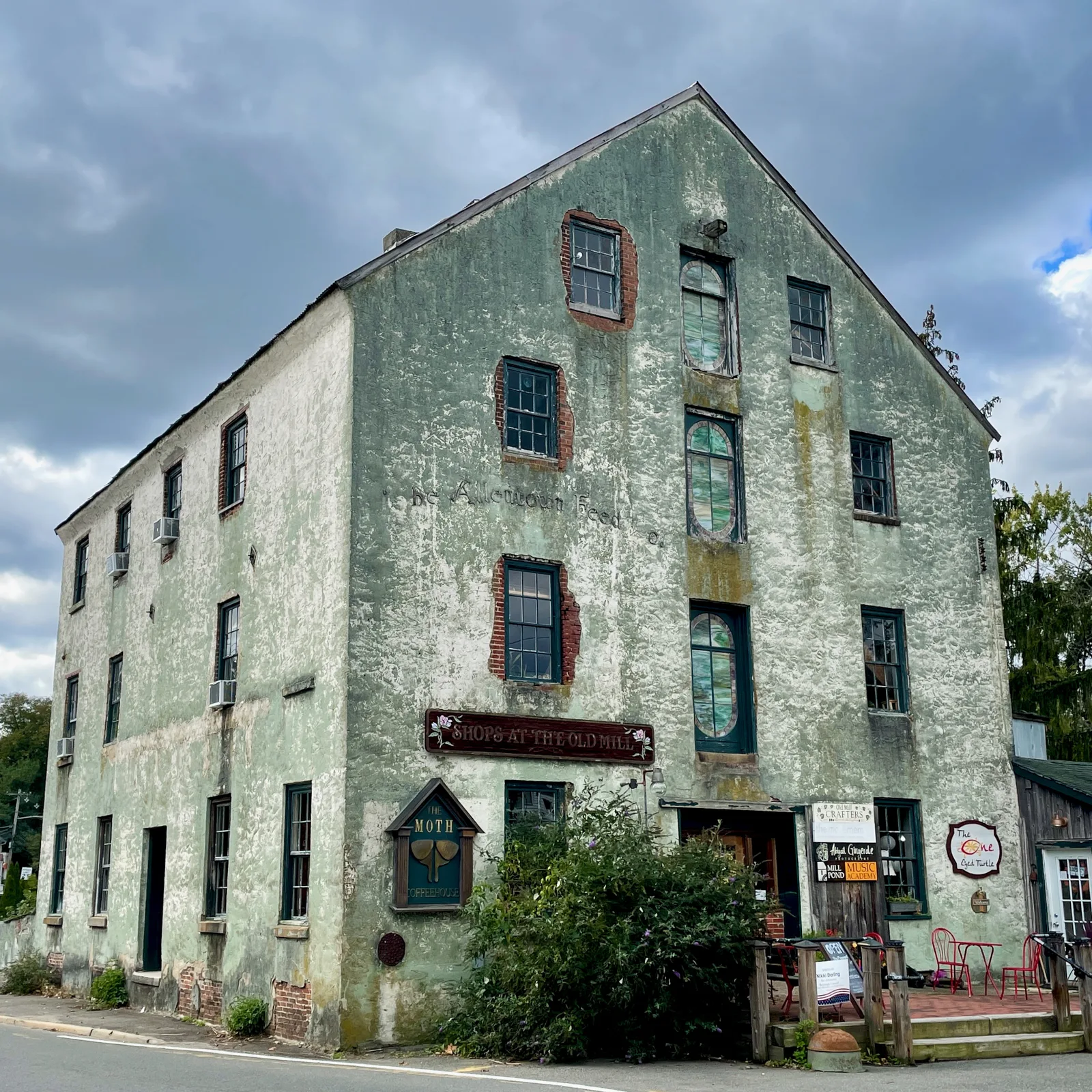 The tall stucco Allentown Mill building with shop signs at street level