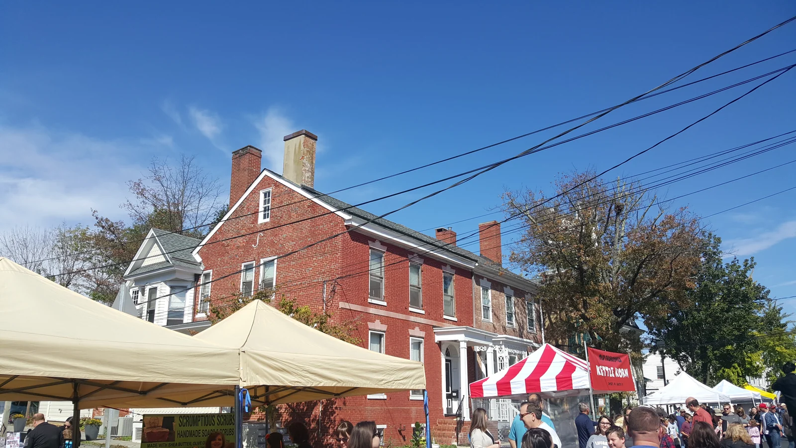 Festival tents and shoppers in front of a red brick historic building on Main Street