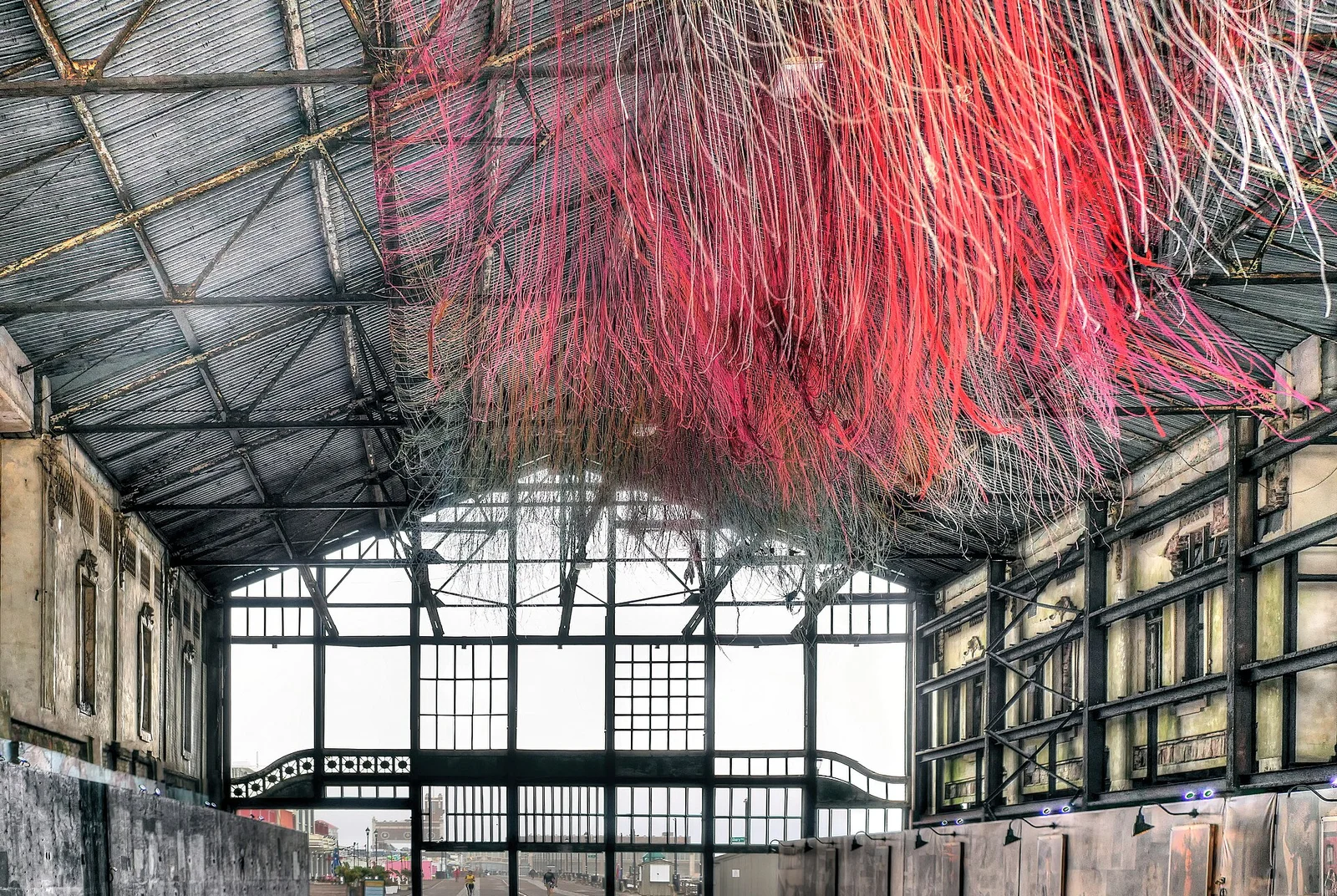 Strands of pink and red yarn hanging from the iron roof of the open-air Casino walkway