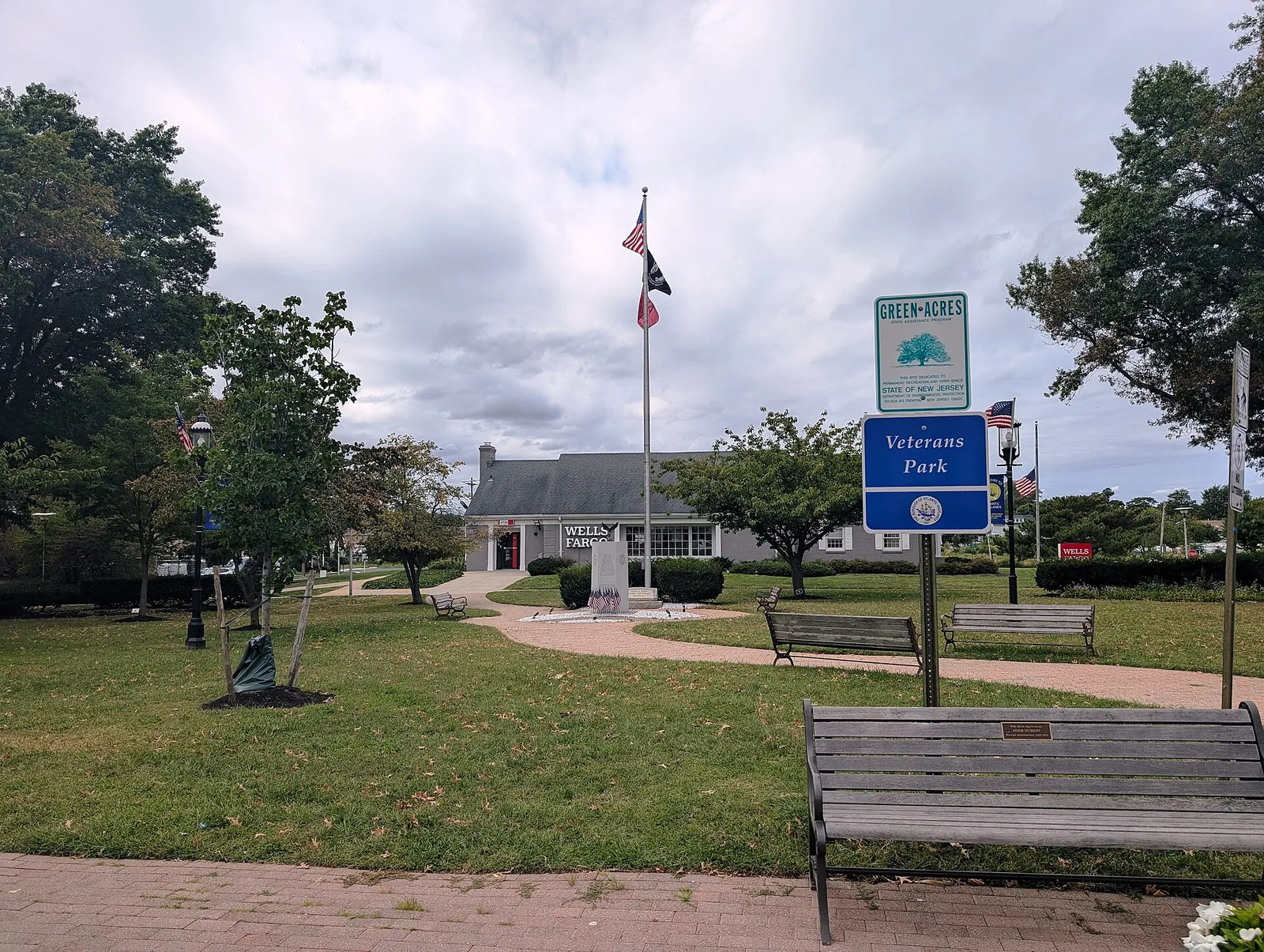 Veterans Park on First Avenue, with a flagpole, benches and brick paths across a green lawn