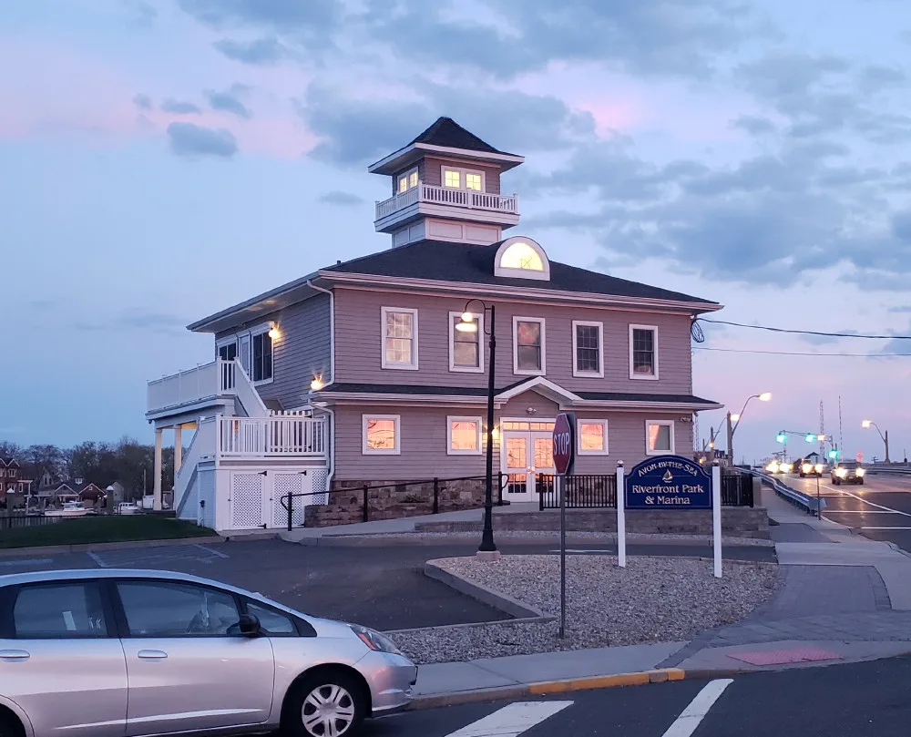 The marina building with its cupola at Avon Riverfront Park and Marina on the Shark River, lit at dusk