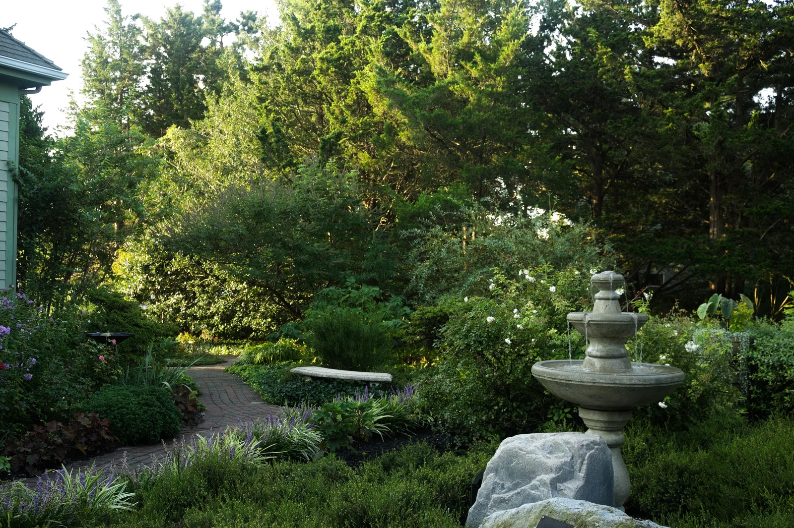 Brick paths, shrubs and a stone fountain in the gardens beside the Barnegat Light Museum