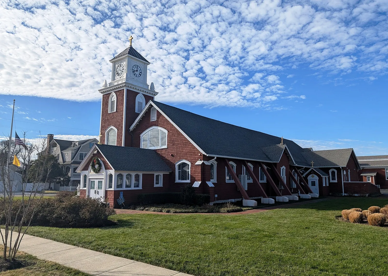 Red brick church with a white clock tower under a blue sky with scattered clouds