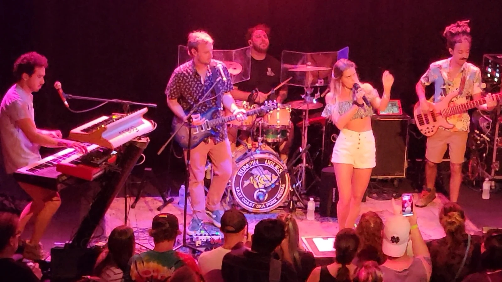 A reggae rock band playing under pink stage lights to a packed crowd at Bird & Betty's