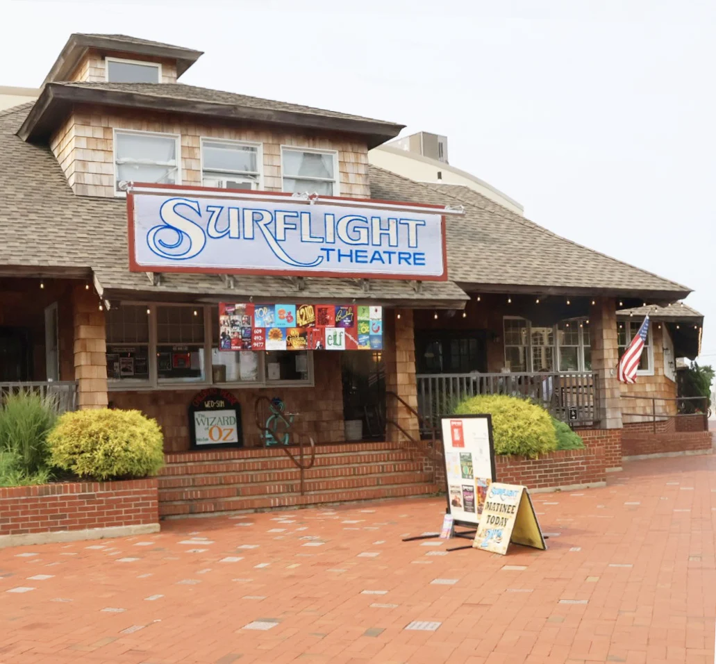 Surflight Theatre's shingled front with its script sign, show posters and a brick plaza