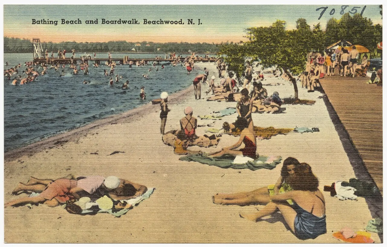 Vintage postcard of sunbathers on a riverfront beach beside a wooden boardwalk