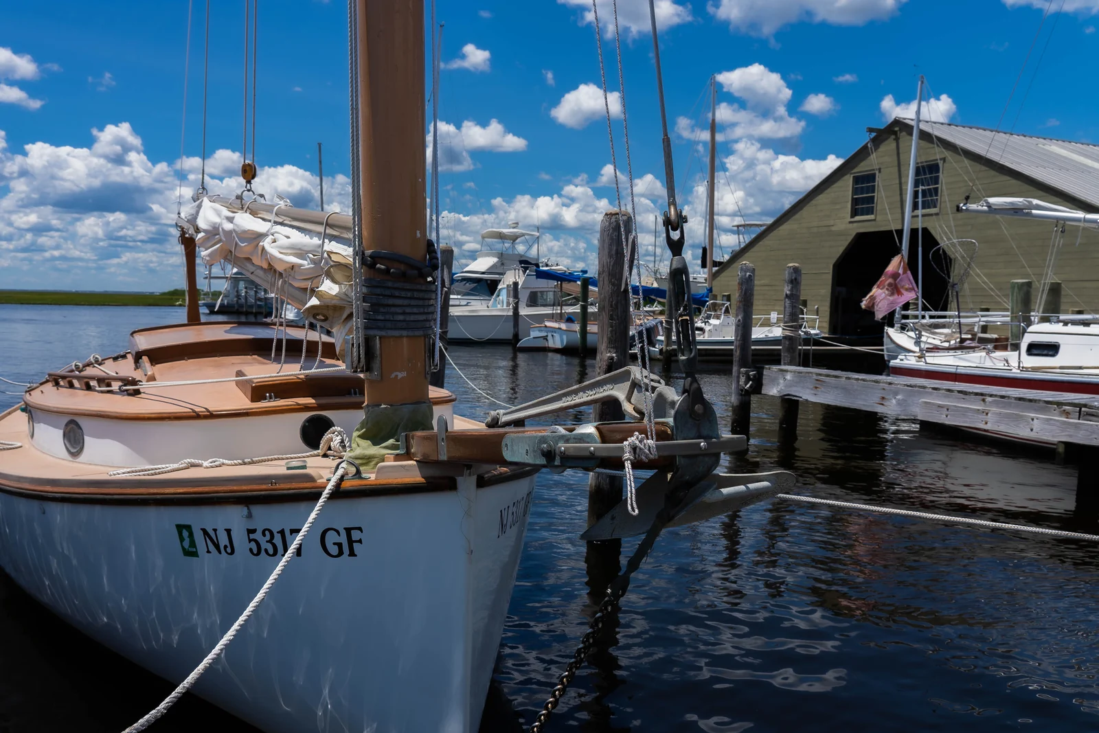 Wooden catboat tied at the dock beside the historic Beaton boatyard boathouse