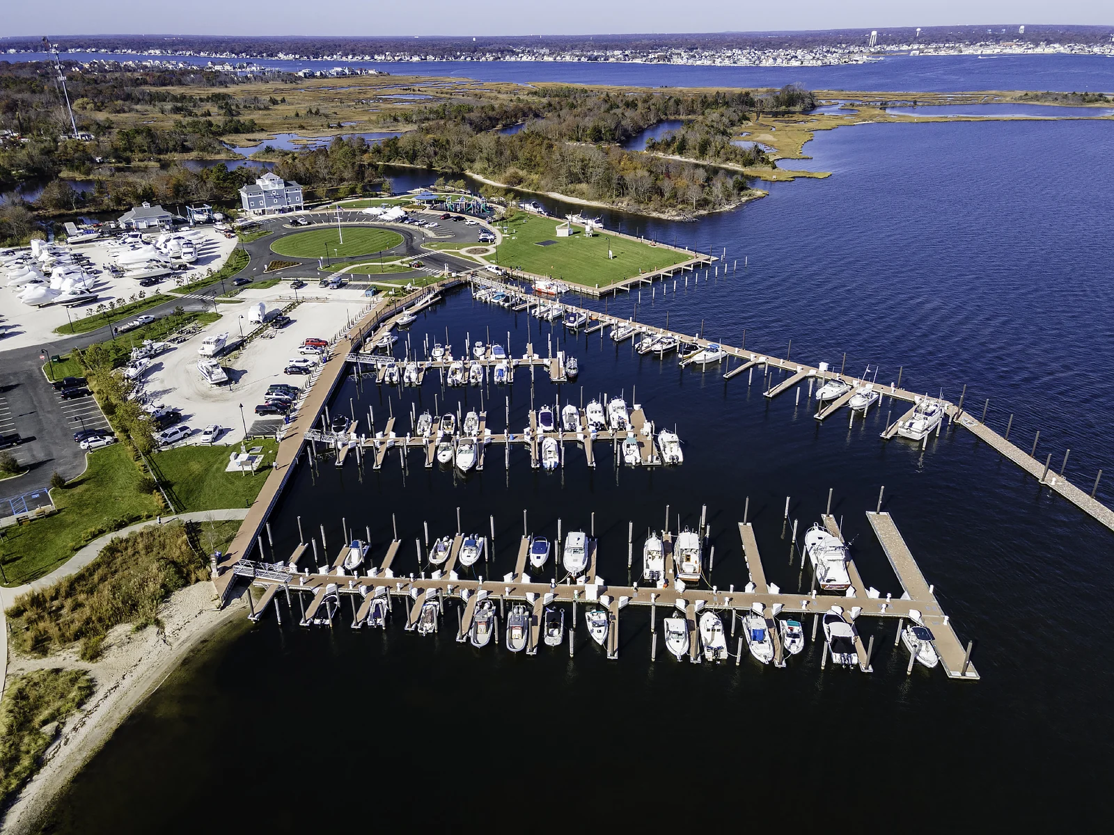 Aerial view of Traders Cove Marina and Park with boat slips, a green lawn and Barnegat Bay