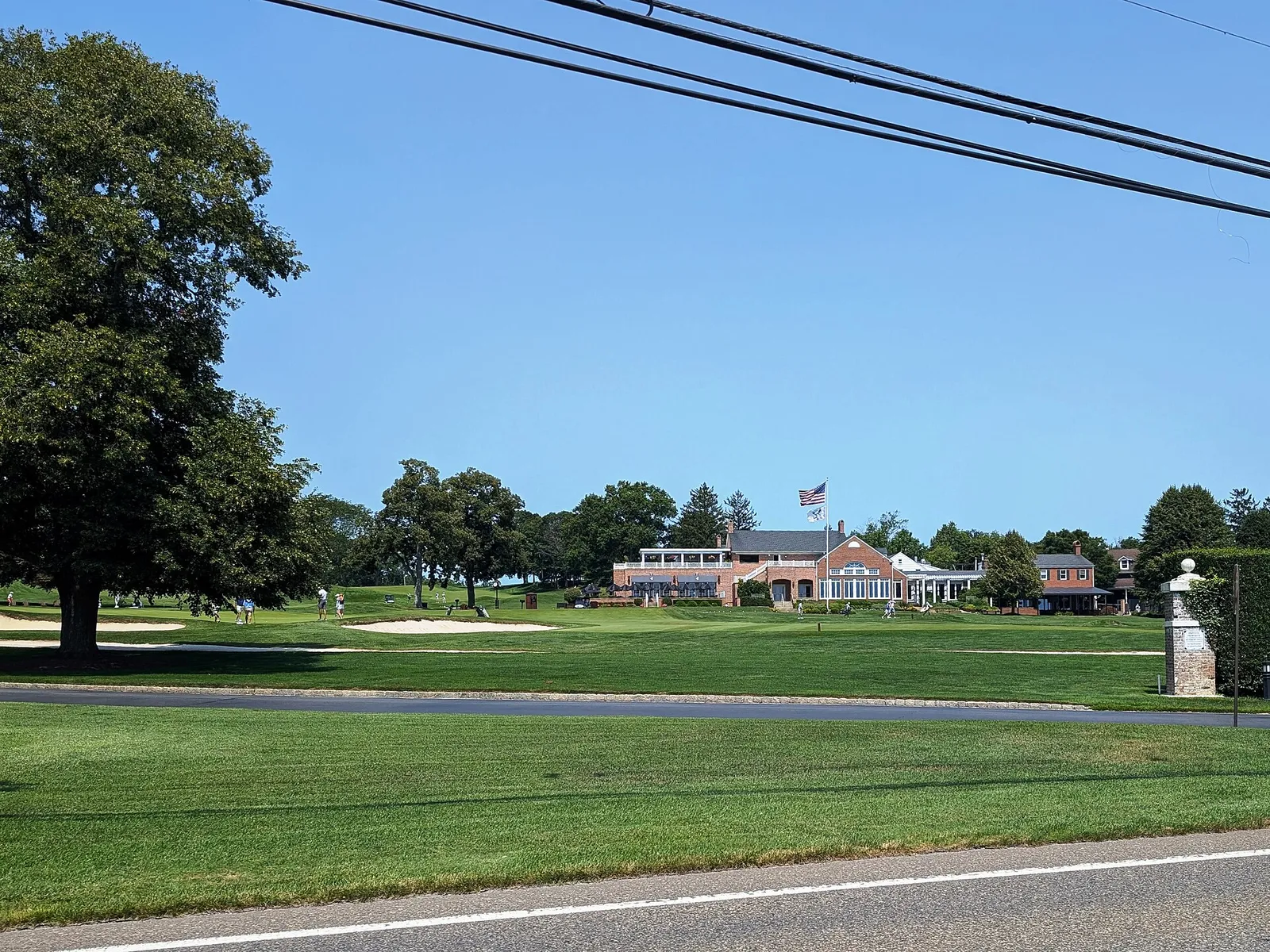The Manasquan River Golf Club clubhouse beyond a wide green lawn and shade trees