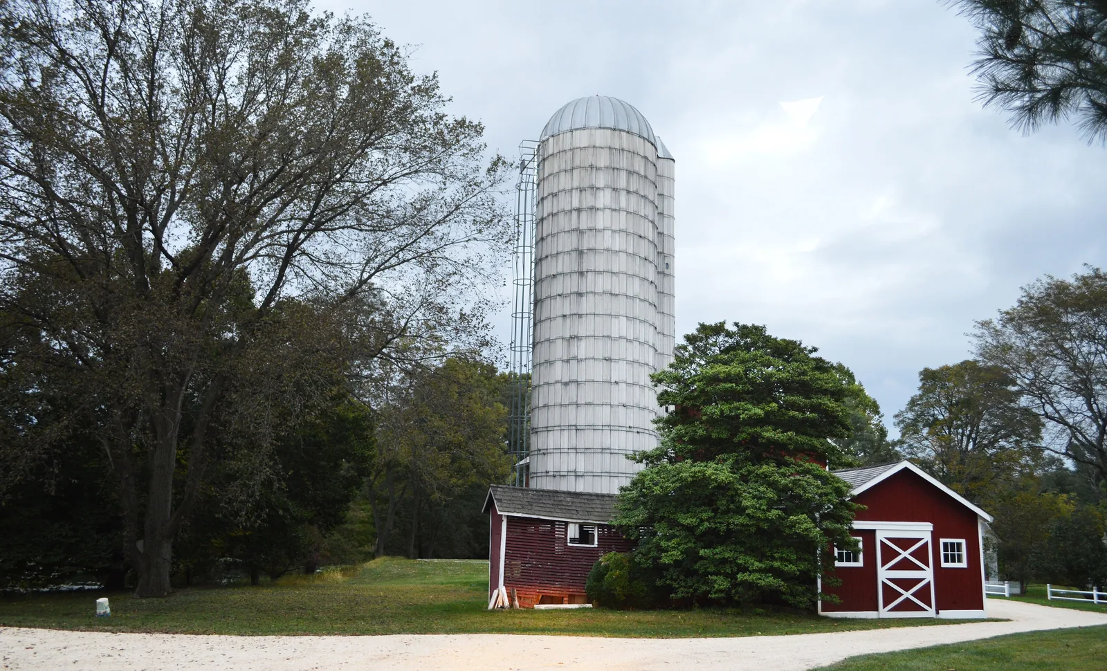 The Probasco-Dittner Farmstead with a tall silo and a red barn under large trees
