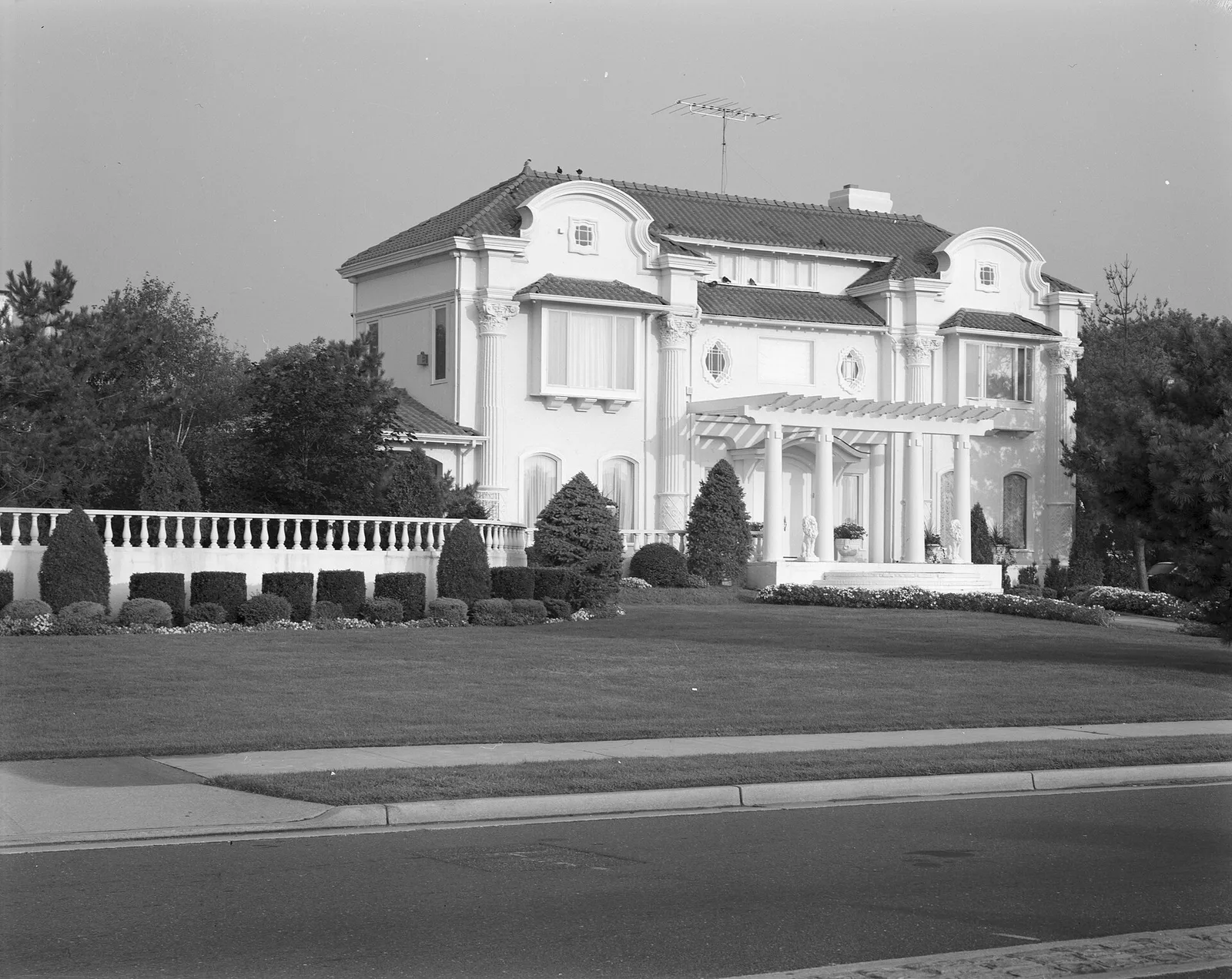 A large white stucco house with a balustrade wall and manicured shrubs on Ocean Boulevard in Deal, black and white survey photograph