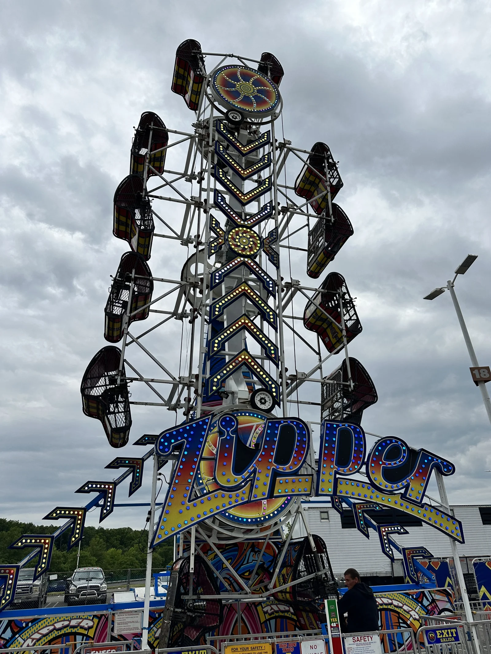 The lit-up Zipper carnival ride rising against a cloudy sky at a carnival in the Monmouth Mall parking lot