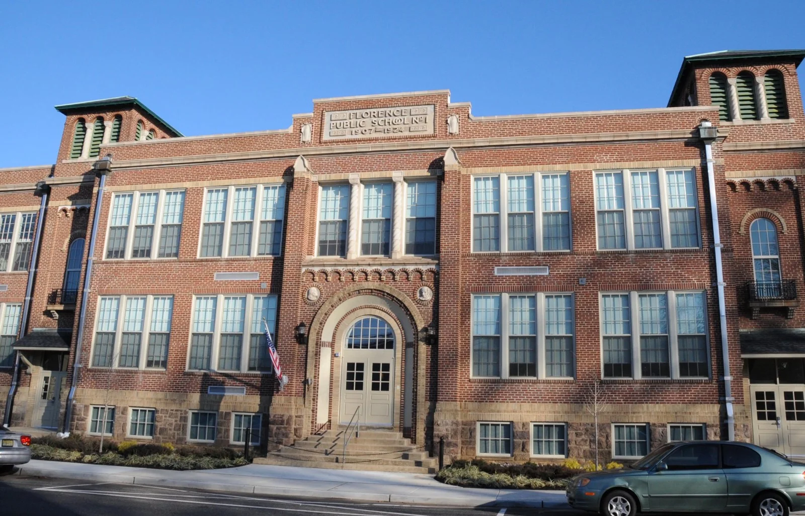 A three-story brick schoolhouse with arched windows and a stone entrance, labeled Florence Public School No. 1