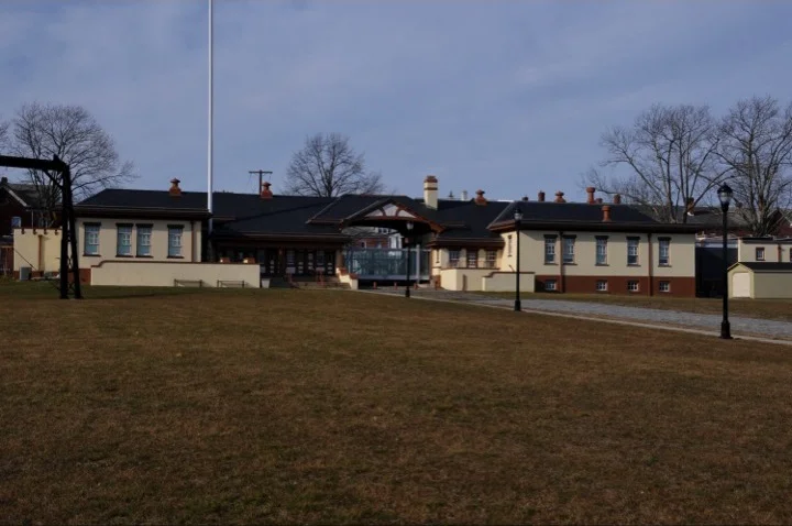 The long low brick gatehouse of the former Roebling steel mill, now the Roebling Museum, behind a wide lawn