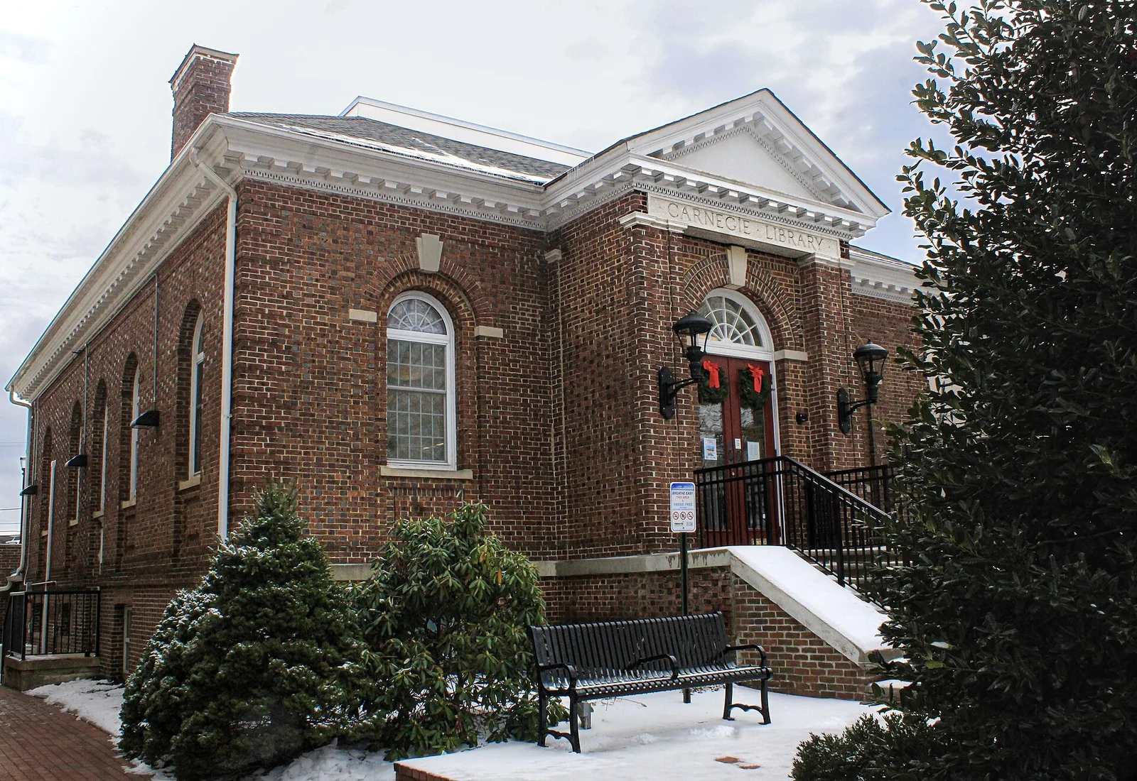 The brick Carnegie library building of the Freehold Public Library with arched windows, light snow on the ground