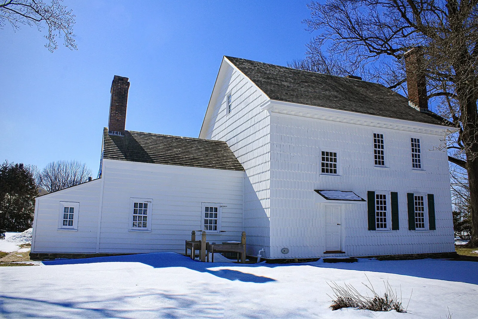 The white clapboard Hankinson-Moreau-Covenhoven House in winter sun with snow on the lawn