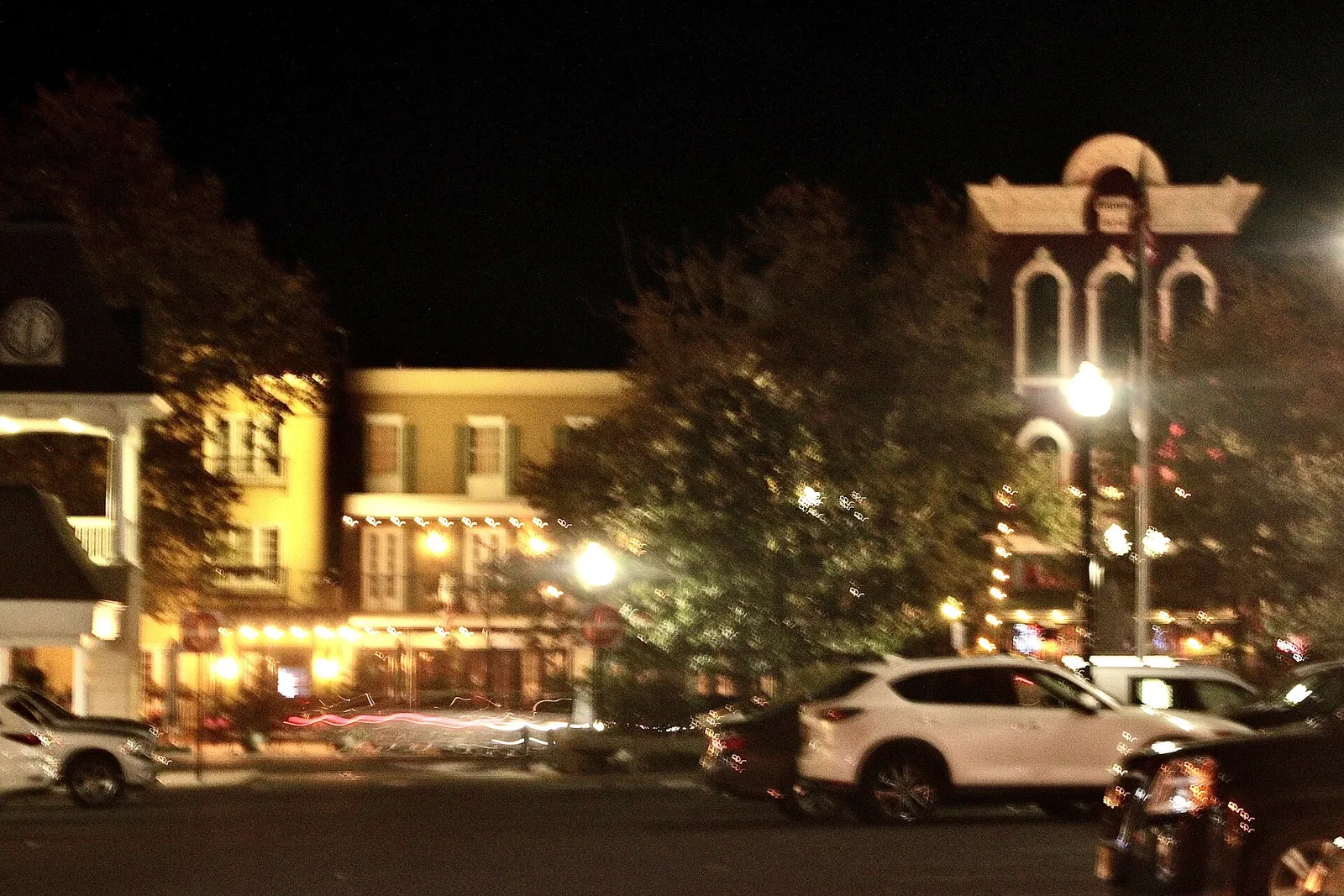 Historic Main Street storefronts and a towered building glowing with lights at night