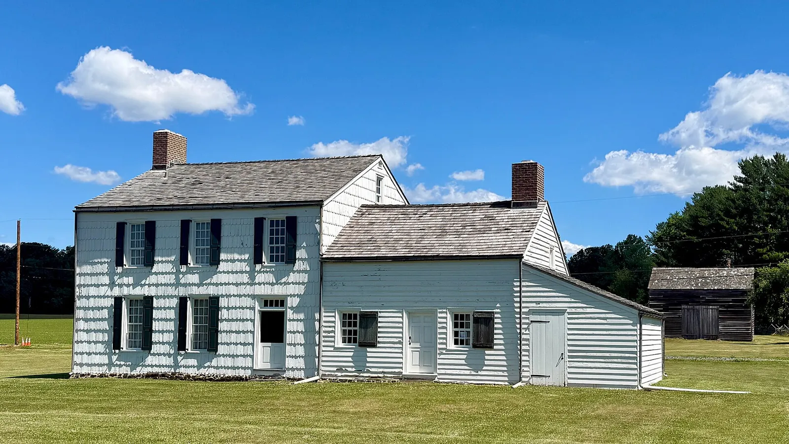 The white two-story John Craig House and its barn under a blue sky