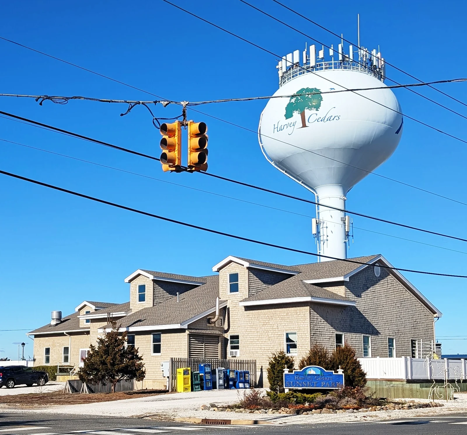 The Harvey Cedars water tower, painted with a cedar tree, above a shingled building and the Sunset Park sign