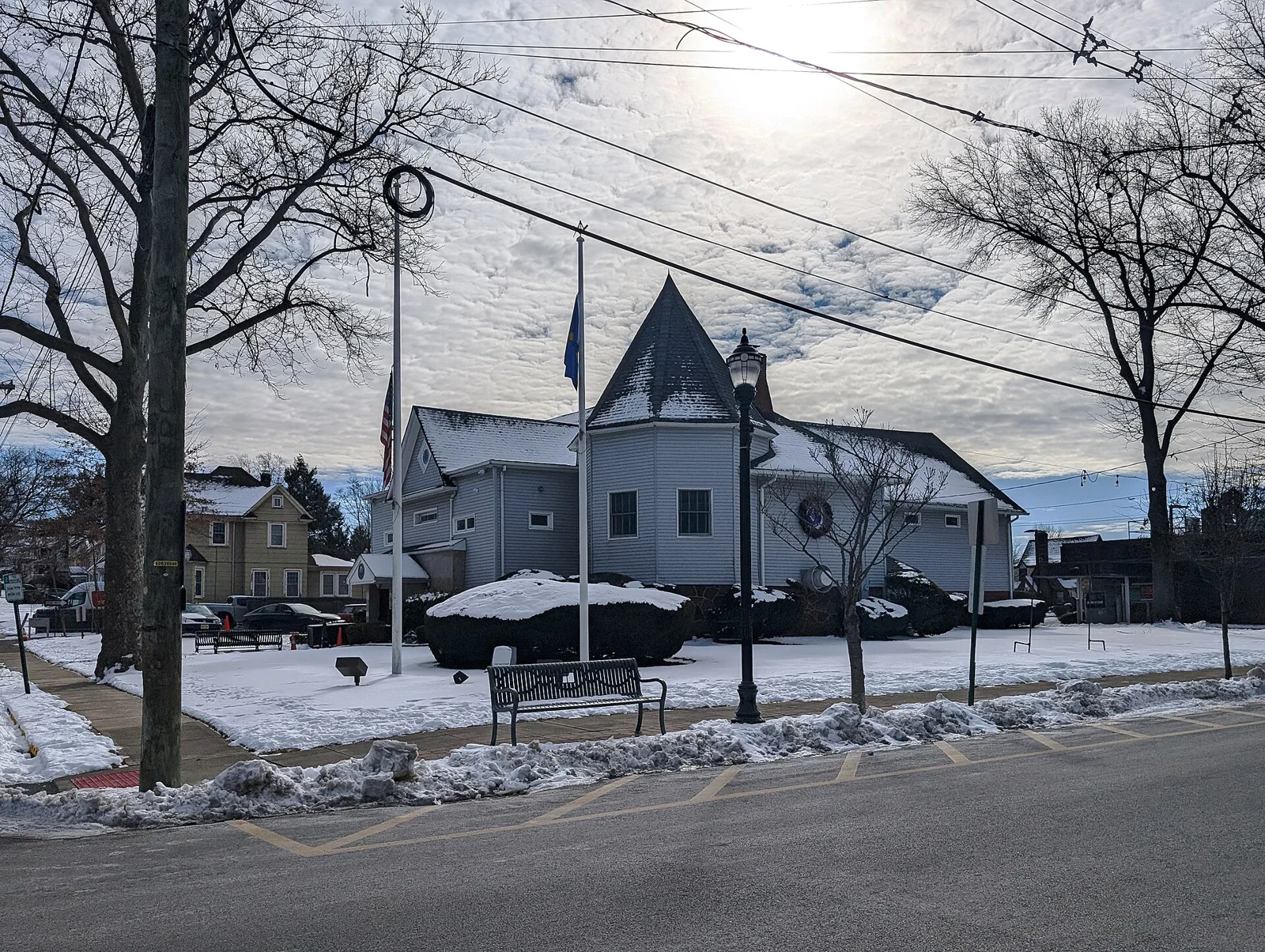 A white Victorian building with a pointed turret and a front lawn in early winter