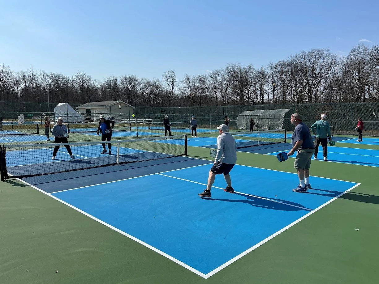 Players in doubles games on blue and green pickleball courts at Veterans Park