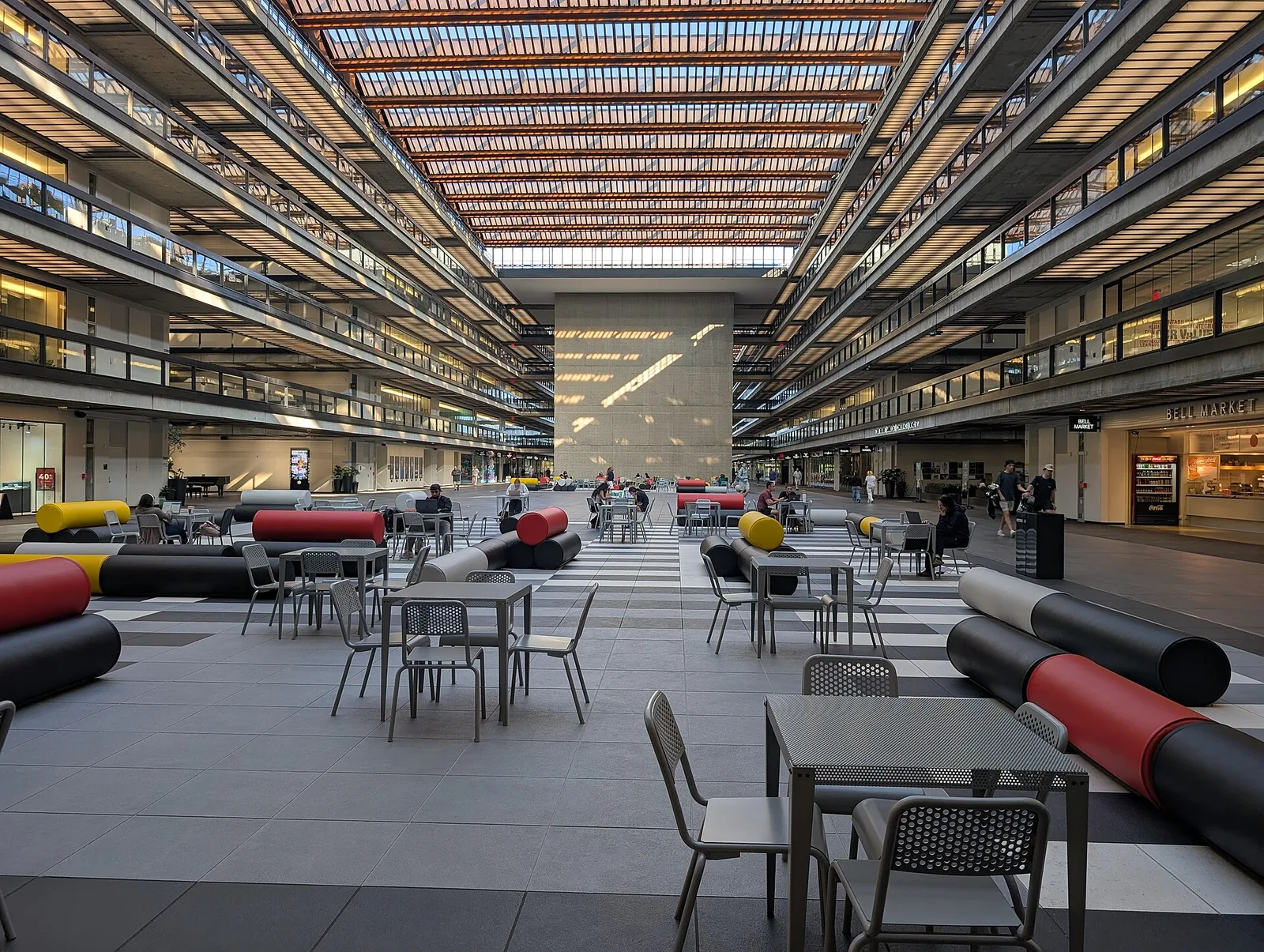 The long sunlit interior atrium of Bell Works with tables, seating and walkways on every floor