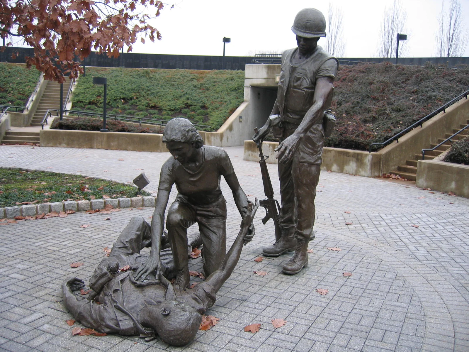 Bronze statue of a standing soldier and a figure kneeling beside a fallen soldier, on a brick plaza at the New Jersey Vietnam Veterans' Memorial