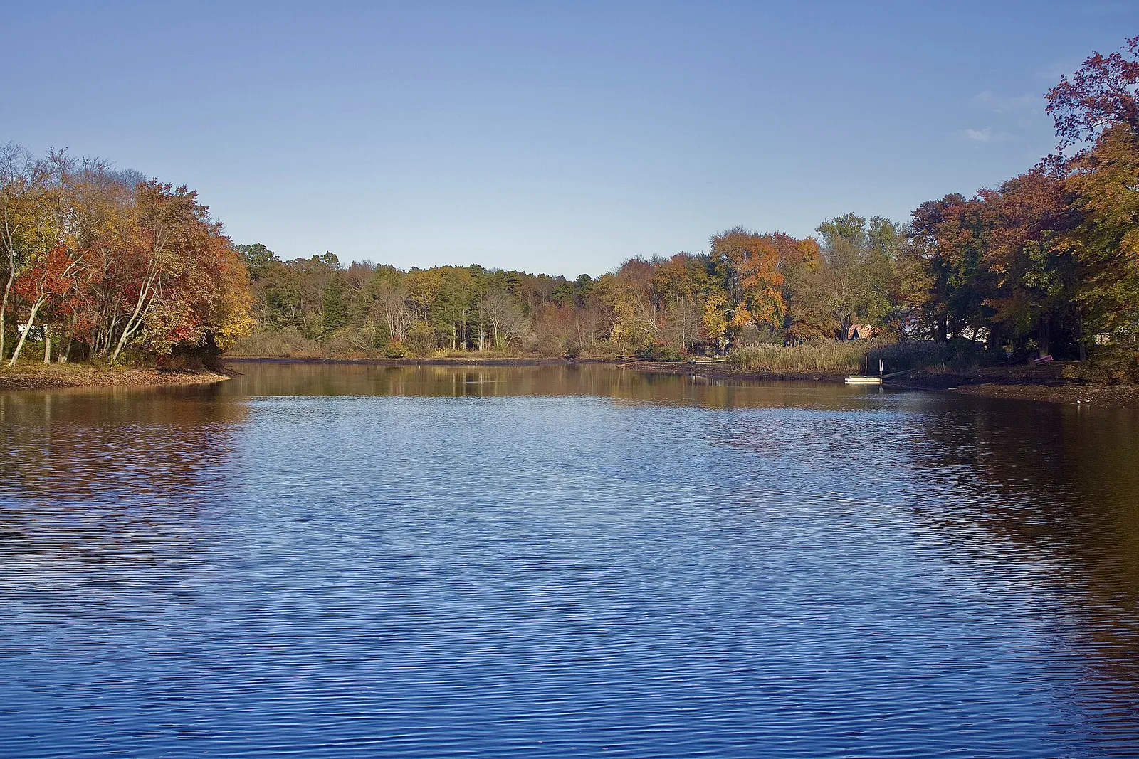 Aldrich Lake with fall foliage along the far shore under a blue sky