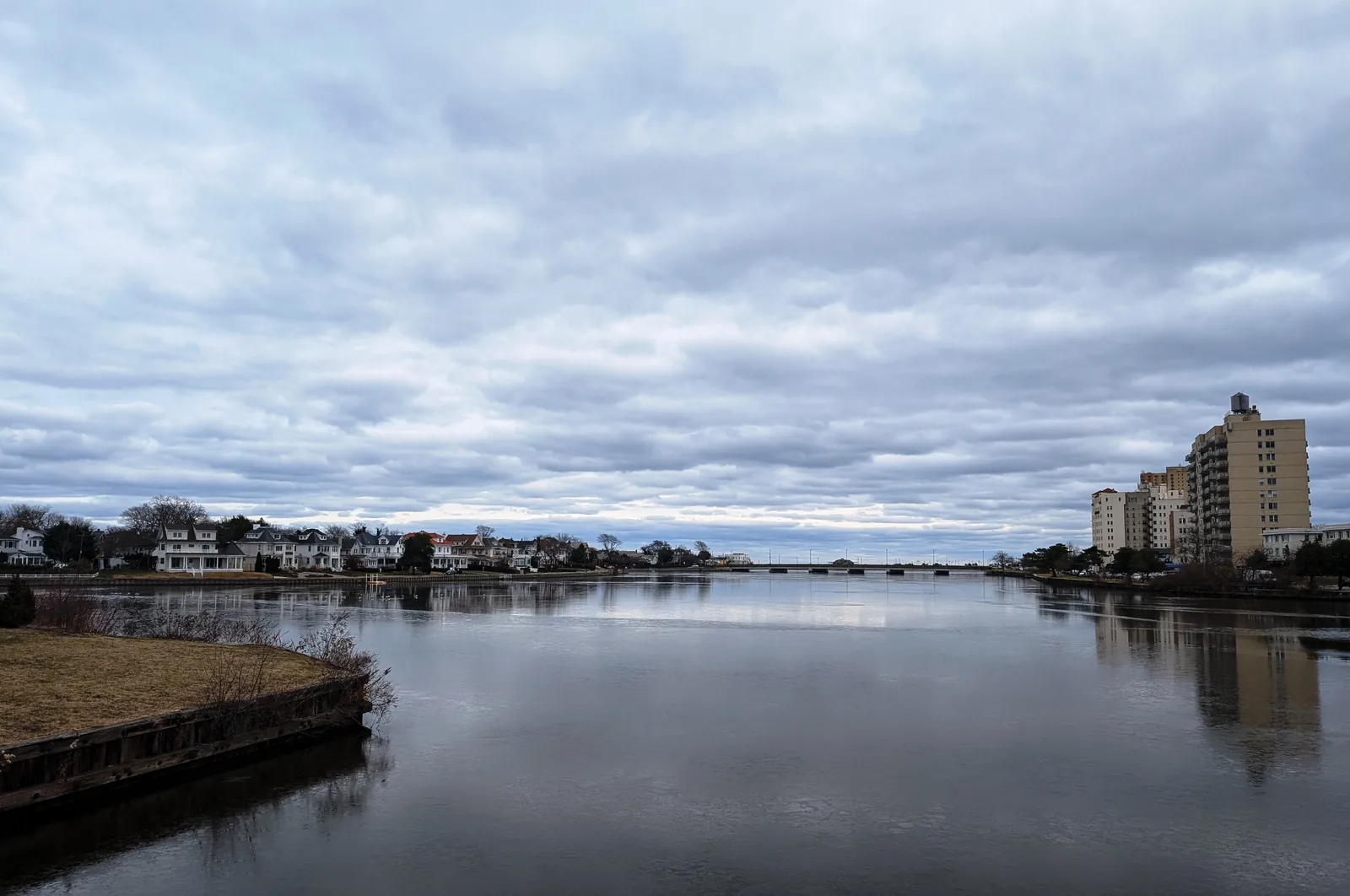 Deal Lake looking east from the County Route 15 causeway, with Interlaken homes along the left shore under a cloudy sky